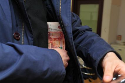 Мужчина прячет деньги во внутренний карман пиджака.