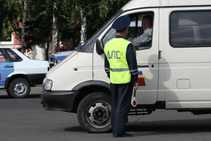 Инспектор ДПС на дороге проверяет у водителя документы.