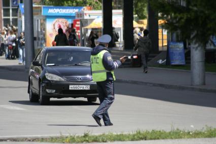 Инспектор ДПС на дороге проверяет у водителя документы.