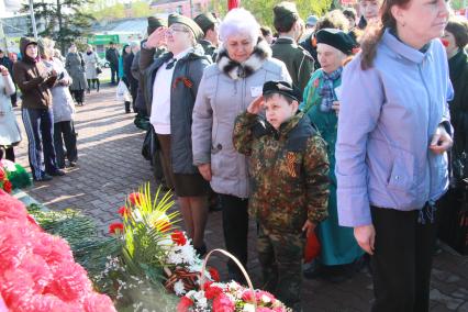 Возложение цветов к памятнику. Ребенок, мальчик отдает честь.