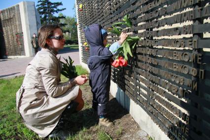 Ребенок прикрепляет цветы к Мемориалу павшим в годы Великой Отечественной войны рядом с фамилией не вернувшегося с войны родственника.