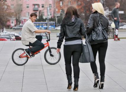 Парень на велосипеде засмотрелся на двух молодых красивых девушек.