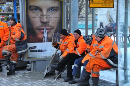 Гастарбайтеры сидят на автобусной остановке.