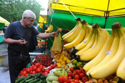 Ярмарка выходного дня. На снимке: мужчина возле палатки с фруктами и овощами.