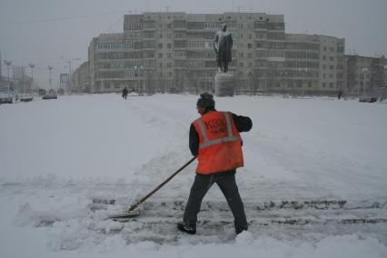 Виды Магадана. На снимке: дворник расчищает снег на площади города.