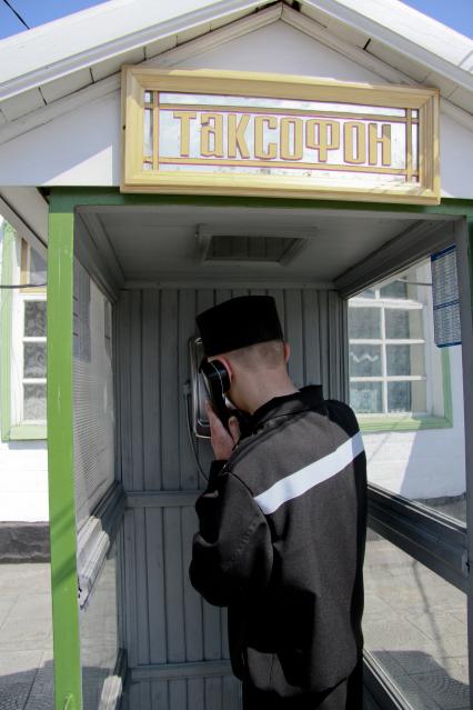 Колония общего режима. На снимке: таксофон для осужденных. Заключенный стоит в телефонной кабинке и разговаривает по телефону.
