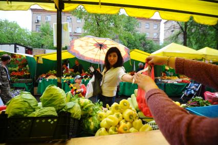 Ярмарка выходного дня. На снимке: девушка покупает овощи.