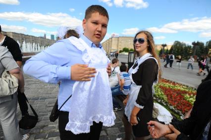 Школьники отмечают последний звонок в школе. На снимке: одноклассницы одевают на парня школьный фартук.