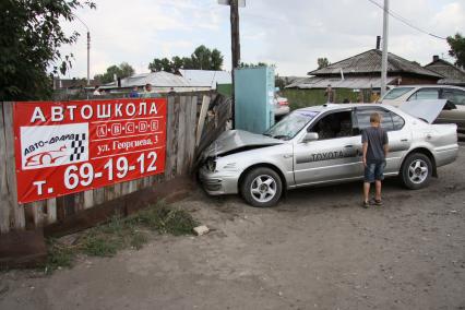 Автомобиль врезался в забор с рекламным плакатом автошколы.