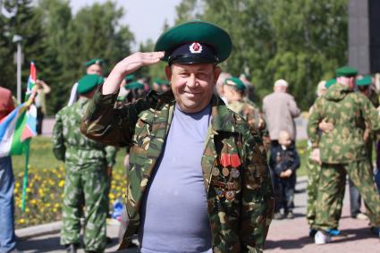 Мужчина в форме пограничника с наградами приветствует фотографа.