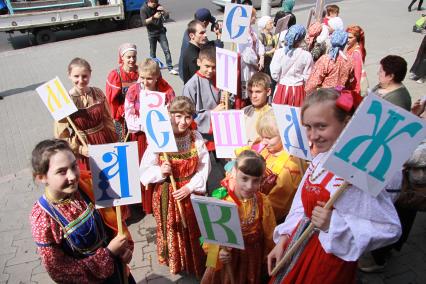 Дети в национальных русских одеждах с буквами алфавита в руках.