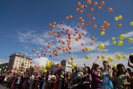 Выпускники запускают воздушные шары в небо.