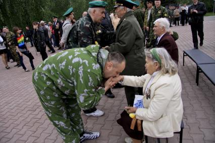 Мужчина в форме пограничника целует женщине ветерану руку.