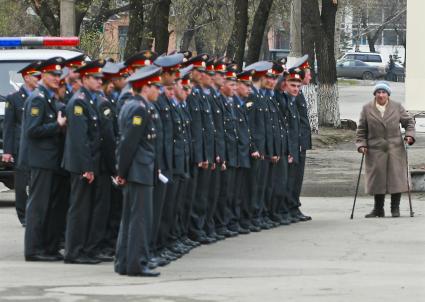 Строй милиционеров (полицейских) и бабушка на костылях.