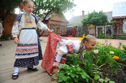 Девочка нюхает на клумбе цветок нарцисса.