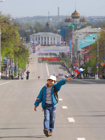 На первомайской демонстрации в Туле ребенок с российским флагом идет по улице города.
