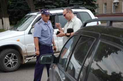 Инспектор ДПС проводит проверку документов у автолюбителя.