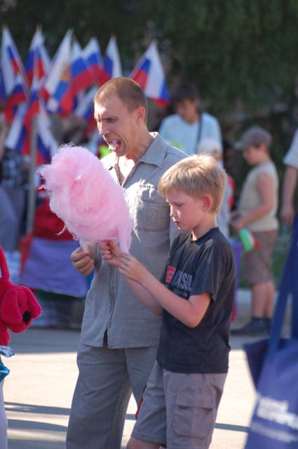 Ребенок с отом едят сахарную вату.