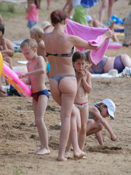 На пляже молодая мама с двумя детьми.