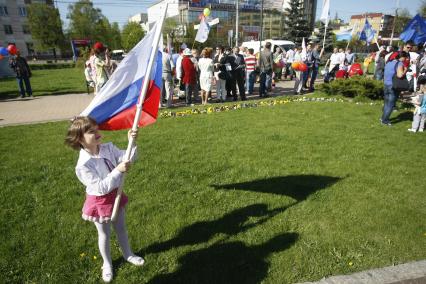 Ребенок с российским флагом стоит на газоне.