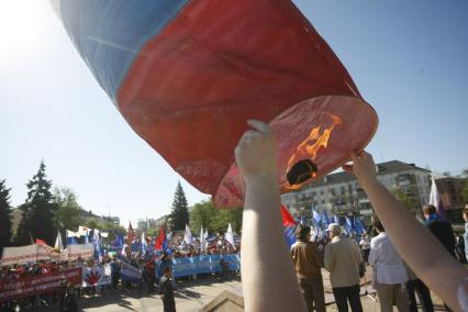 Человек запускает небесный фонарь в цвет российского флага.