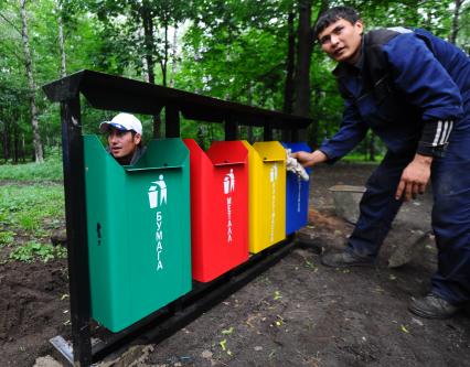 Гастарбайтеры устанавливают новые мусорки для раздельного сбора мусора в парке Кузьминки.