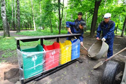 Гастарбайтеры устанавливают новые мусорки для раздельного сбора мусора в парке Кузьминки.