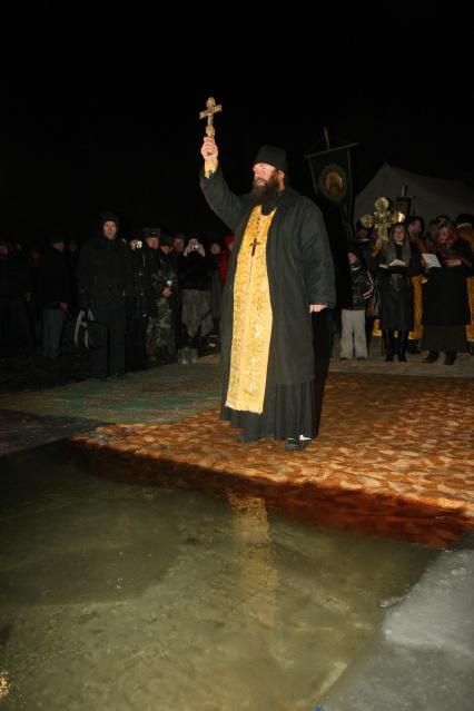 Священник освящает воду перед крещением.