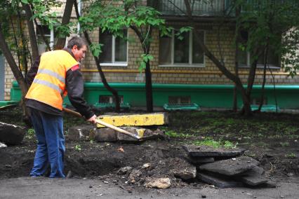 Гастарбайтер разбивает асфальт во дворе дома.