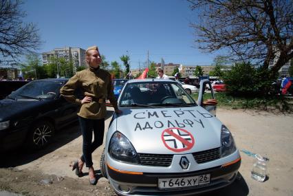 Девушка в пилотке и гимнастерке времен ВОВ стоит рядом с автомобилем на котором написано: `Смерть Адольфу`.