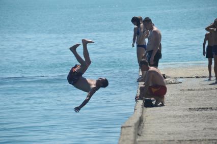 Дети прыгают в воду с понтона.