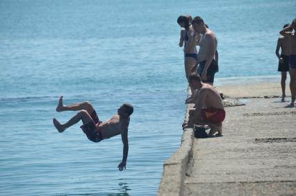 Дети прыгают в воду с понтона.