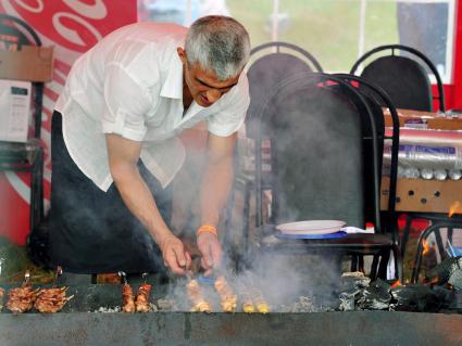 Аэродром `Тушино`. 15-й международный музыкальный фестиваль `Maxidrom`. Мужчина готовит шашлык на углях.