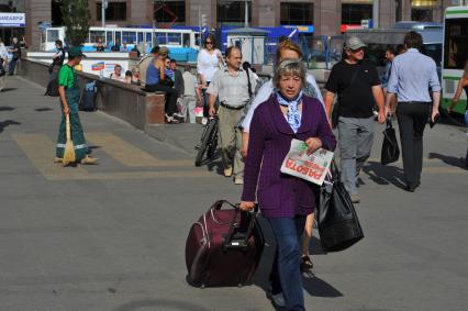 Женщина с дорожной сумкой на городской улице.