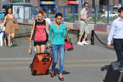 Девушка с дорожной сумкой на городской улице.