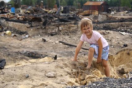 Сгоревшие дома в результате лесных пожаров. Поселок Рустай, Нижегородская область. На снимке: девочка на пепелище.