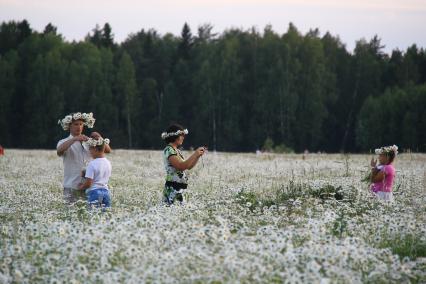 Праздник Ивана Купалы на озере Светлояр, Нижегородская область. На снимке: На поле цветов люди плетут венки из ромашек.