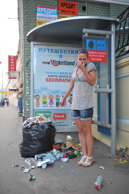 Мусор на улице города. На снимке: девушка на автобусной остановке.