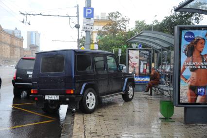 Джип припаркован на тротуаре перед остановкой.