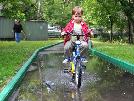 Мальчик на велосипеде едет по луже