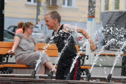 Мальчик забрался в фонтан и играет с водой.