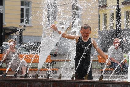 Мальчик забрался в фонтан и играет с водой.