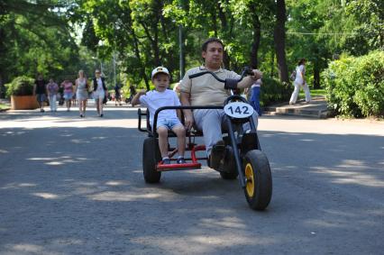 Парк `Сокольники`. На снимке: мужчина с ребенком катаются на велосипеде по парку.
