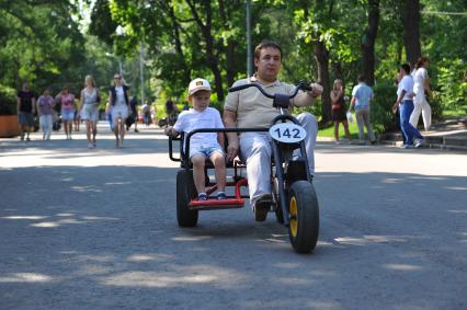 Парк `Сокольники`. На снимке: мужчина с ребенком катаются на велосипеде по парку.