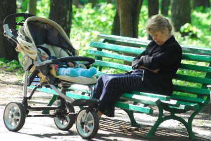 Ребенок уснул в коляске рядом с ним на скамейке уснула бабушка.