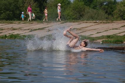 Дети купаются в водоеме, прыгают в воду.