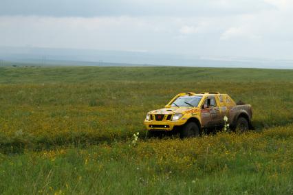 Желтые внедорожник во время прохождения трассы ралли `Шелковый путь`, оказался на поле с желтыми цветами.