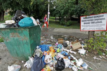 Мусорка в Ставрополе. Мусор вываливается из мусорки напротив плаката о запрете свалки.