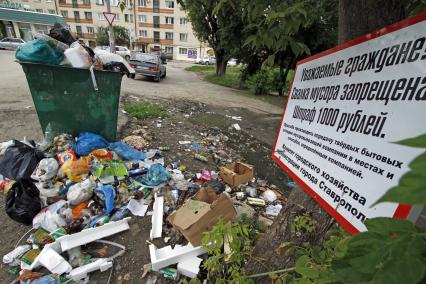 Мусорка в Ставрополе. Мусор вываливается из мусорки напротив плаката о запрете свалки.