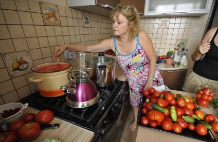Домашнее консервирование.  На снимке: женщина готовит маринад для томатов.